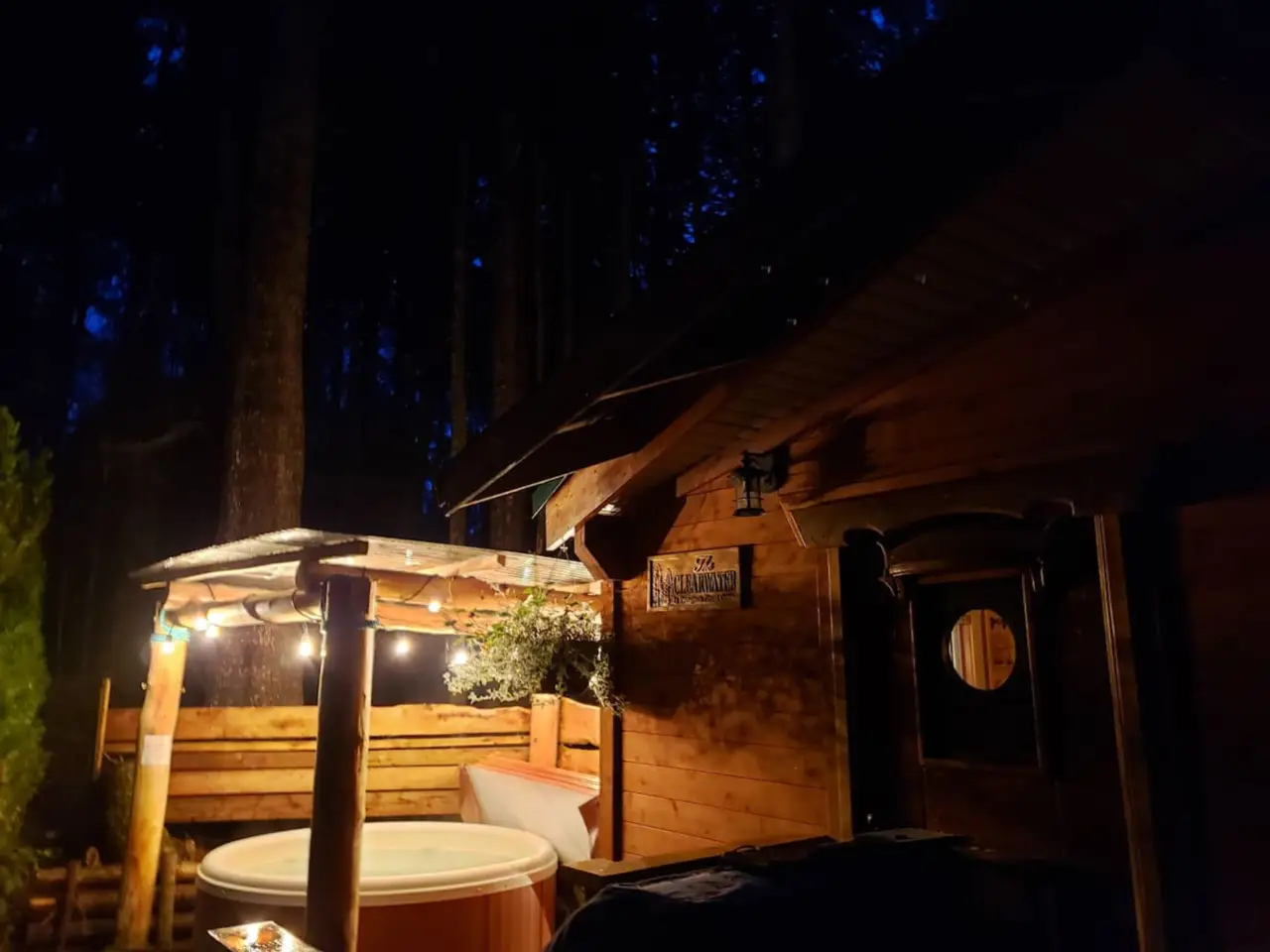 A cozy hot tub surrounded by trees, glowing softly under the night sky, creating a relaxing woodland retreat.
